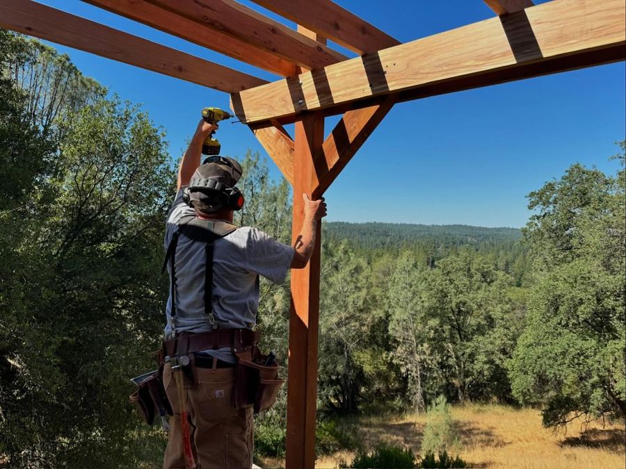 Chip driving a screw overhead into a pergola beam