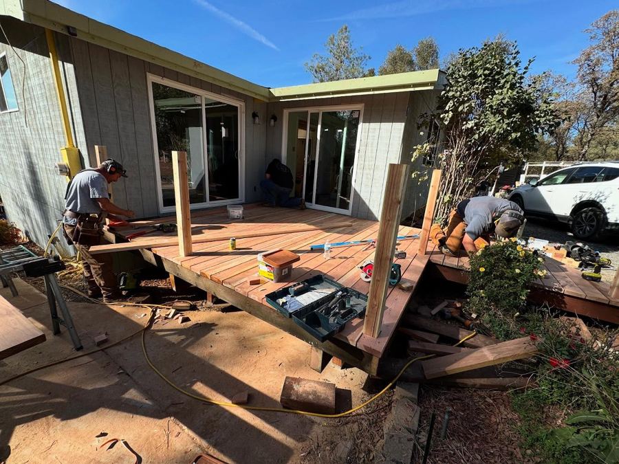 Chip in a grey tee and tool belt marking and cutting boards on a new deck.