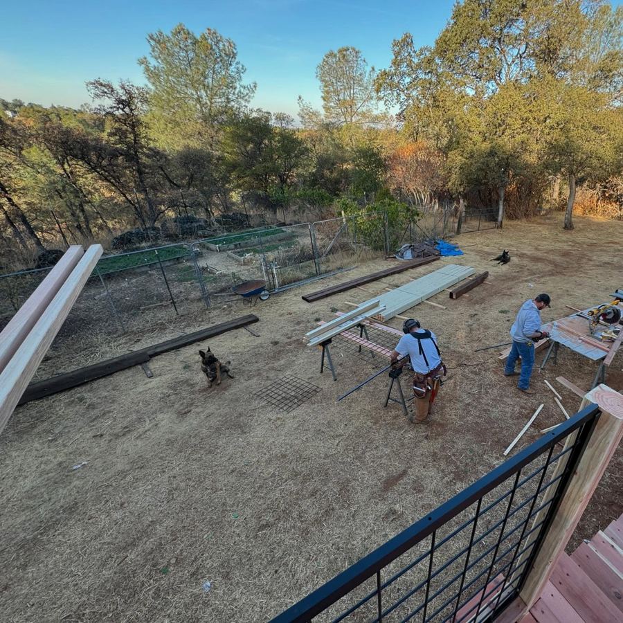Chip in suspenders and tool belt cutting at the sawhorses, shot from above.