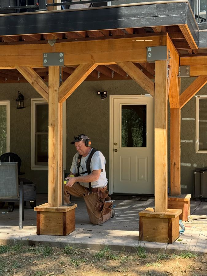 Chip kneeling with a drill at a porch post